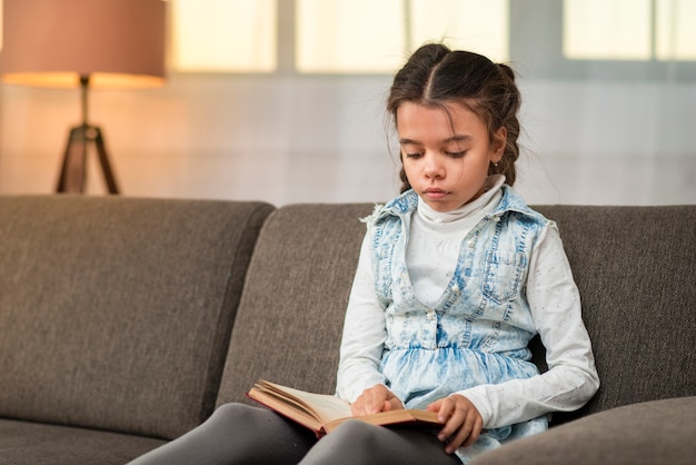 Foto gratuita niña en el sofá leyendo historias