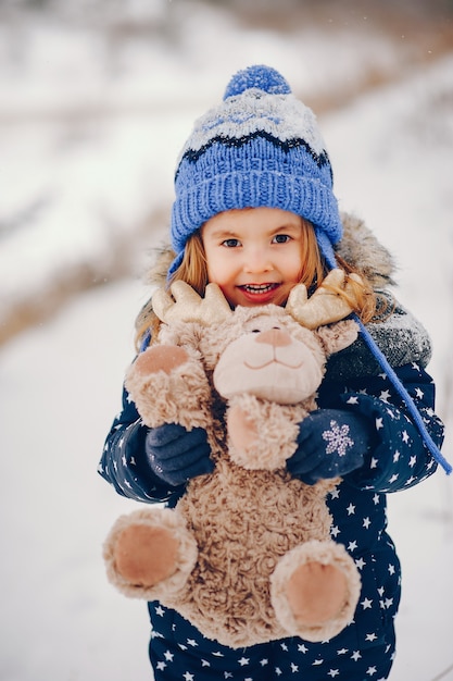 Foto gratuita niña en un sombrero azul jugando en un bosque de invierno