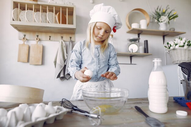 Niña en un sombrero de shef blanco cocinar la masa para galletas