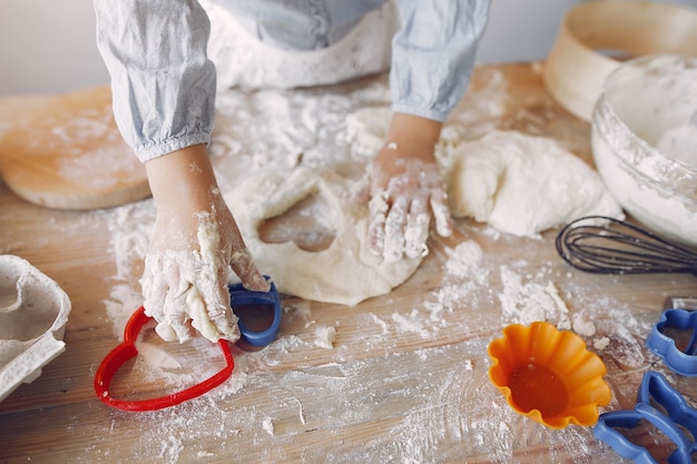 Niña en un sombrero de shef blanco cocinar la masa para galletas