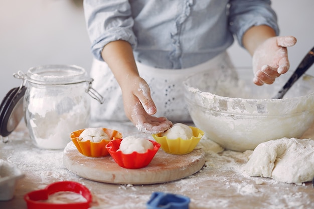 Foto gratuita niña en un sombrero de shef blanco cocinar la masa para galletas