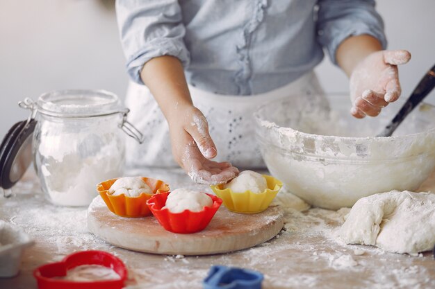 Niña en un sombrero de shef blanco cocinar la masa para galletas