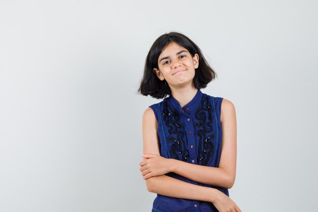 Niña sonriendo mientras mira a la cámara en blusa azul