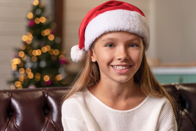 Niña sonriendo mientras usa una gorra de santa