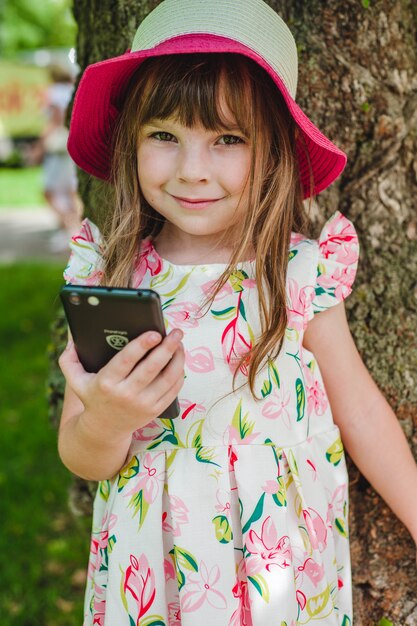 Niña sonriendo con un teléfono inteligente en la mano