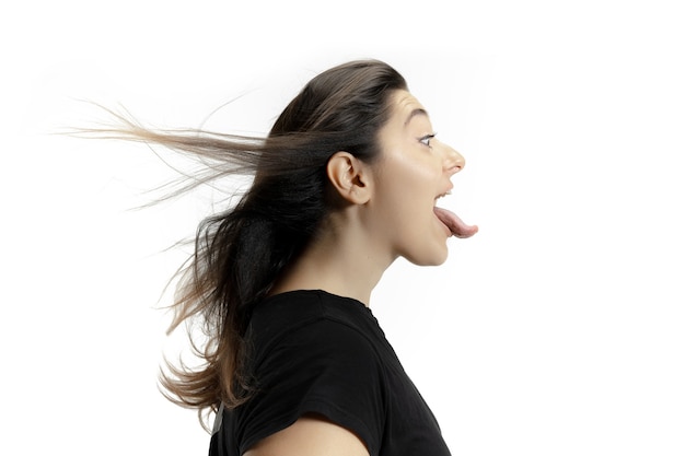 Foto gratuita niña sonriente abriendo la boca y mostrando la lengua gigante grande y larga aislada en la pared blanca