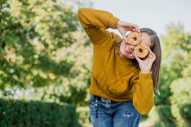 Niña sonriente de ángulo bajo con donas al aire libre