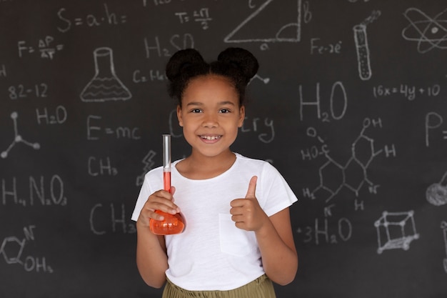 Niña sonriente aprendiendo más sobre química en clase