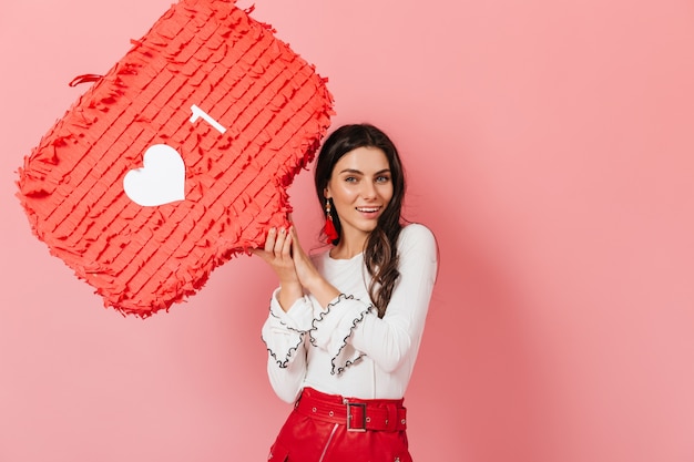 Niña sonriente con aretes largos rojos y falda de cuero con sonrisa demuestra Me gusta de Instagram.