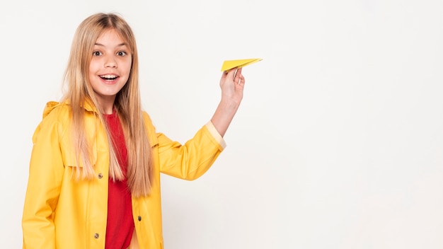 Niña sonriente con avión de papel