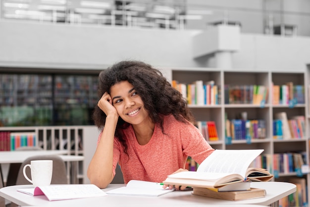 Niña sonriente en la biblioteca estudiando