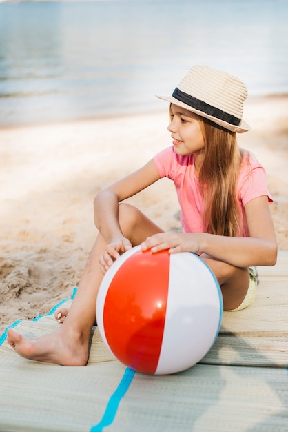 Niña sonriente con bola de viento en la playa