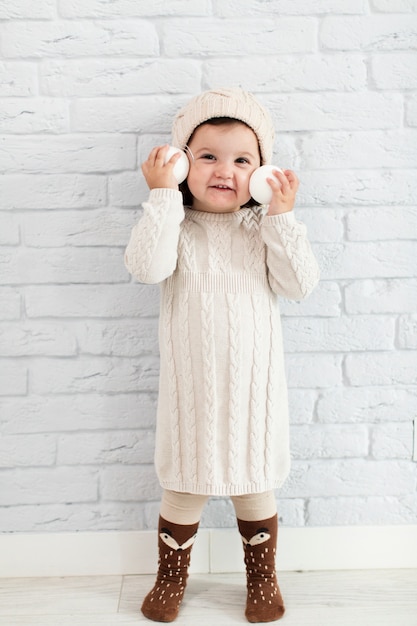 Niña sonriente con bolas de nieve cerca de su cara