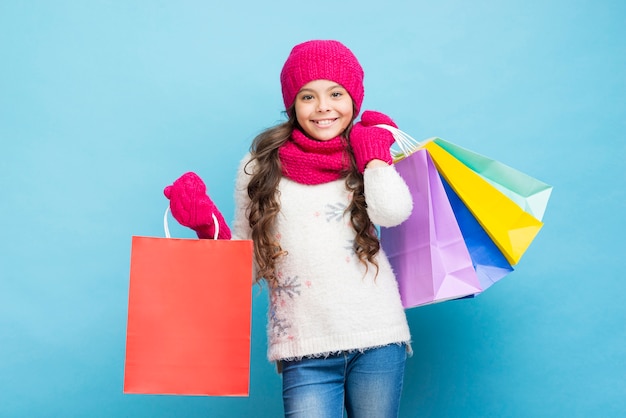 Niña sonriente con bolsas de ropa de invierno