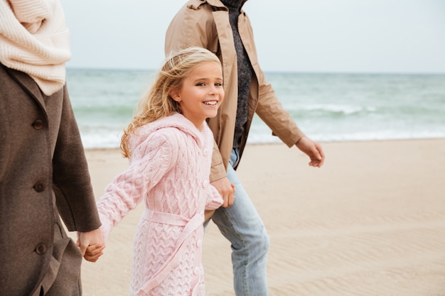 Niña sonriente caminando con sus padres