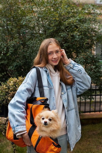 Niña sonriente cargando cachorro en bolsa de tiro medio