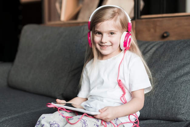 Foto gratuita niña sonriente con cascos en sofá