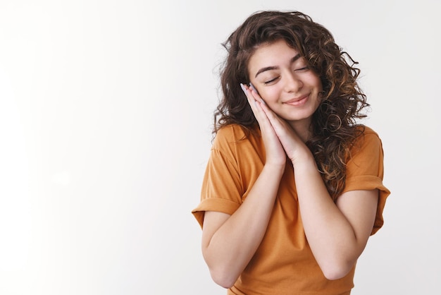 niña sonriente cerrar los ojos somnoliento palma inclinada como almohada acostada soñando despierto pretendiendo dormir