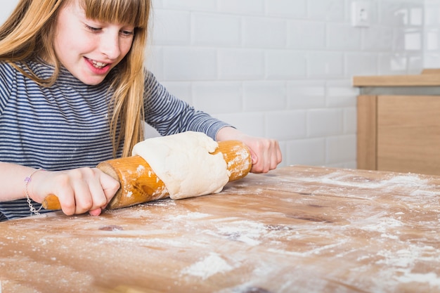 Niña sonriente cocinando masa en la cocina