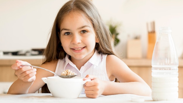 Niña sonriente comiendo cereales para el desayuno