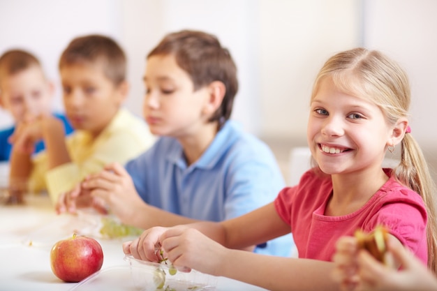 Foto gratuita niña sonriente comiendo uvas