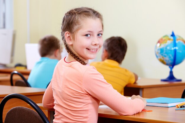 Niña sonriente con compañeros borrosos de fondo