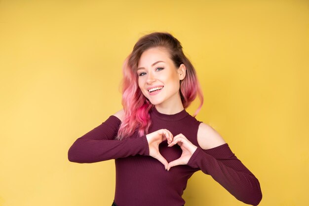 Niña sonriente con corazón forma manos