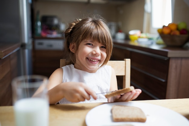 Niña sonriente desayunando en casa