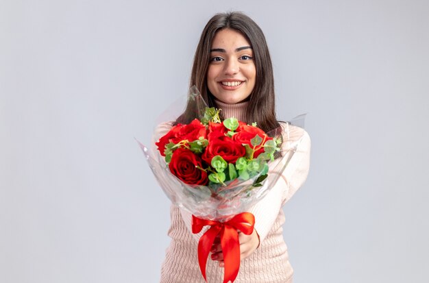 Niña sonriente en el día de San Valentín sosteniendo el ramo en la cámara aislada sobre fondo blanco.