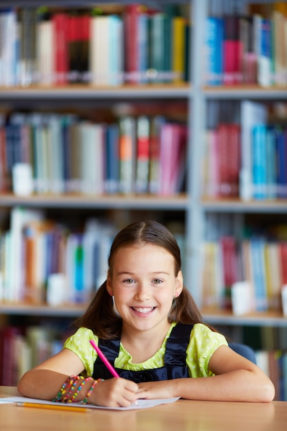 Niña sonriente dibujando en la biblioteca