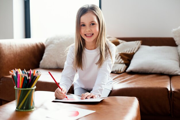 Niña sonriente dibujando una tarjeta del día del padre como sorpresa para su papá