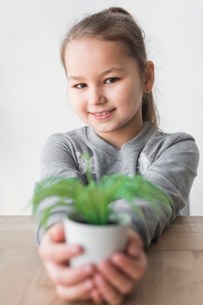 Niña sonriente enseñando planta