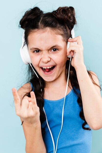 Niña sonriente escuchando música rock en los auriculares