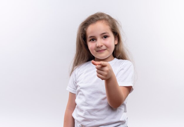 Niña sonriente de la escuela con camiseta blanca que le muestra gesto sobre fondo blanco aislado