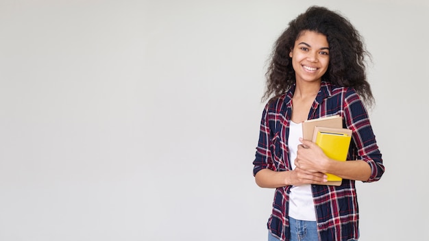 Niña sonriente de espacio de copia con pila de libros