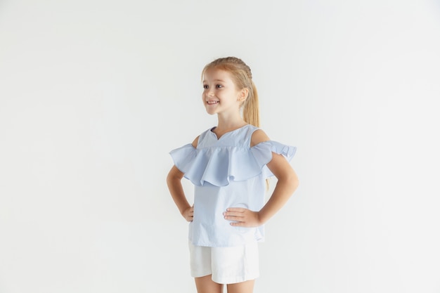 Niña sonriente con estilo posando en ropa casual aislado en el espacio en blanco. Modelo de mujer rubia caucásica. Las emociones humanas, la expresión facial, la infancia.