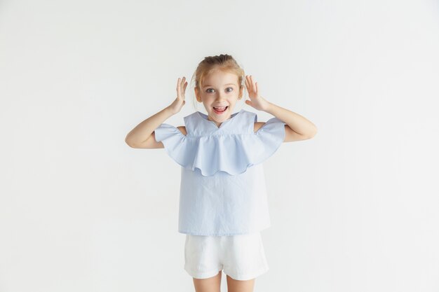 Niña sonriente con estilo posando en ropa casual aislado en el espacio en blanco. Modelo de mujer rubia caucásica. Las emociones humanas, la expresión facial, la infancia.