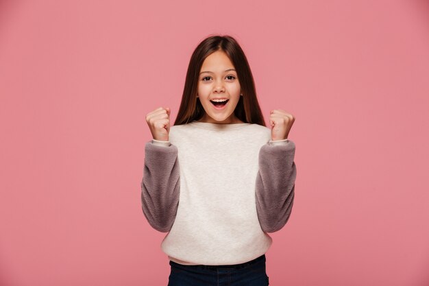 Niña sonriente haciendo gesto ganador mientras mira