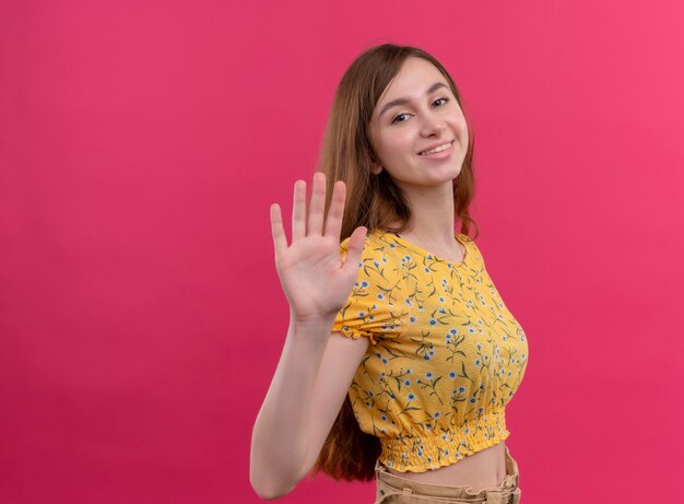 Niña sonriente haciendo gesto de hola en la pared rosa aislada con espacio de copia