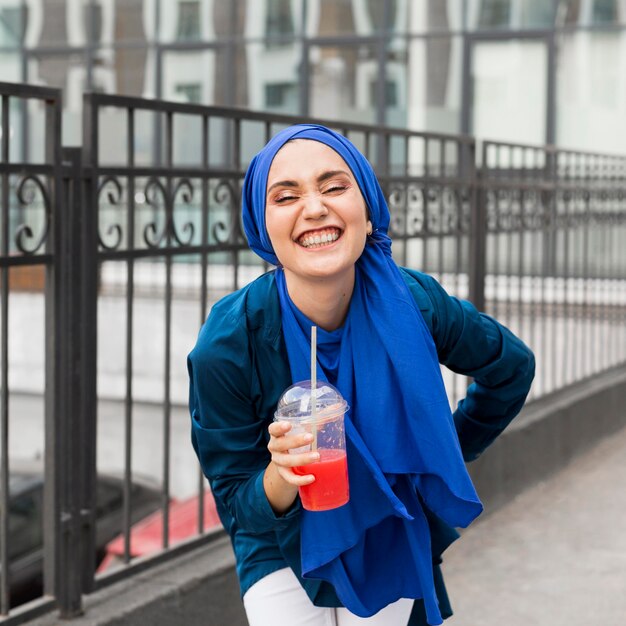 Niña sonriente con un hijab y sosteniendo un batido