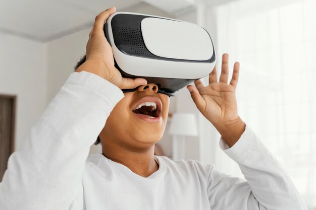 Niña sonriente jugando con casco de realidad virtual en casa