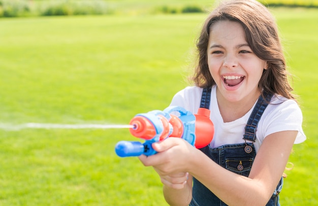 Niña sonriente jugando con pistola de agua