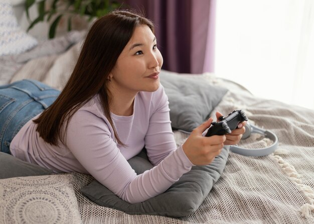 Niña sonriente jugando videojuegos en la cama