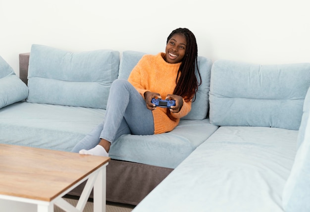 Niña sonriente jugando videojuegos en el sofá