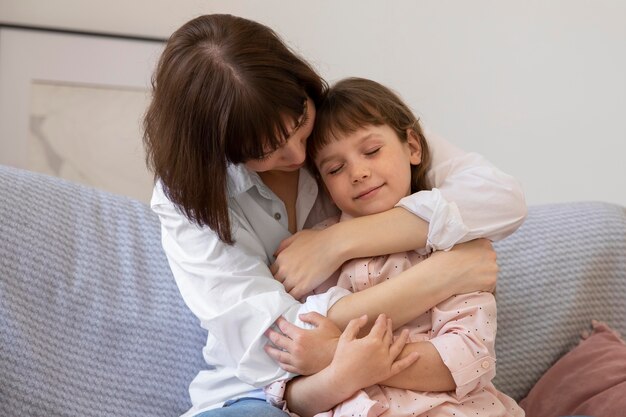 Niña sonriente y madre en tiro medio de sofá