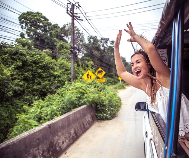 Foto gratuita niña sonriente mira por la ventana de un taxi, tuk-tuk