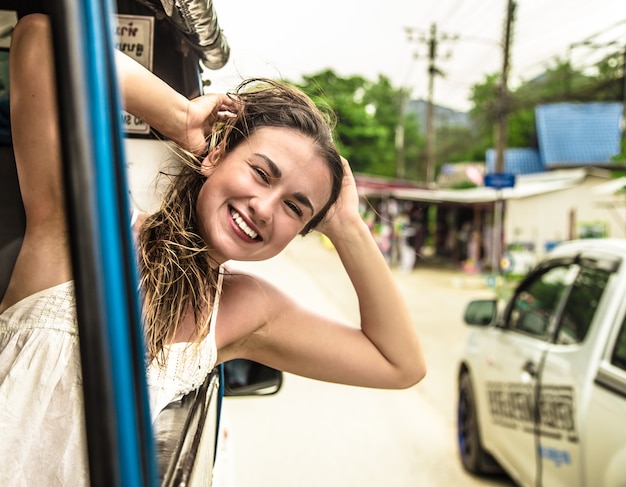 Foto gratuita niña sonriente mira por la ventana de un taxi, tuk-tuk