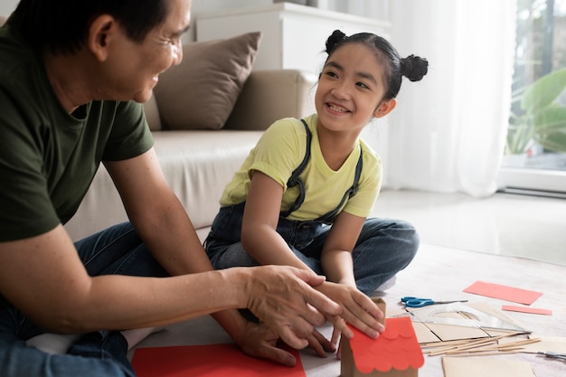 Niña sonriente y padre haciendo casa de papel