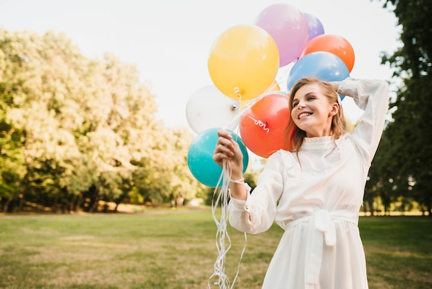 Niña sonriente en el parque con globos