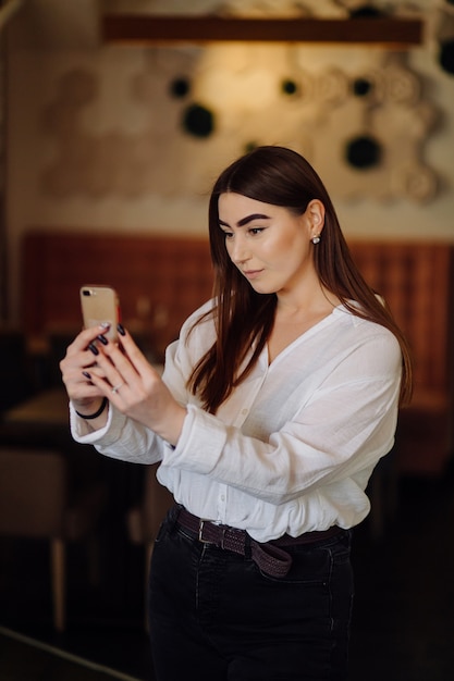 Niña sonriente pasar tiempo en un café de la calle con gadget digital